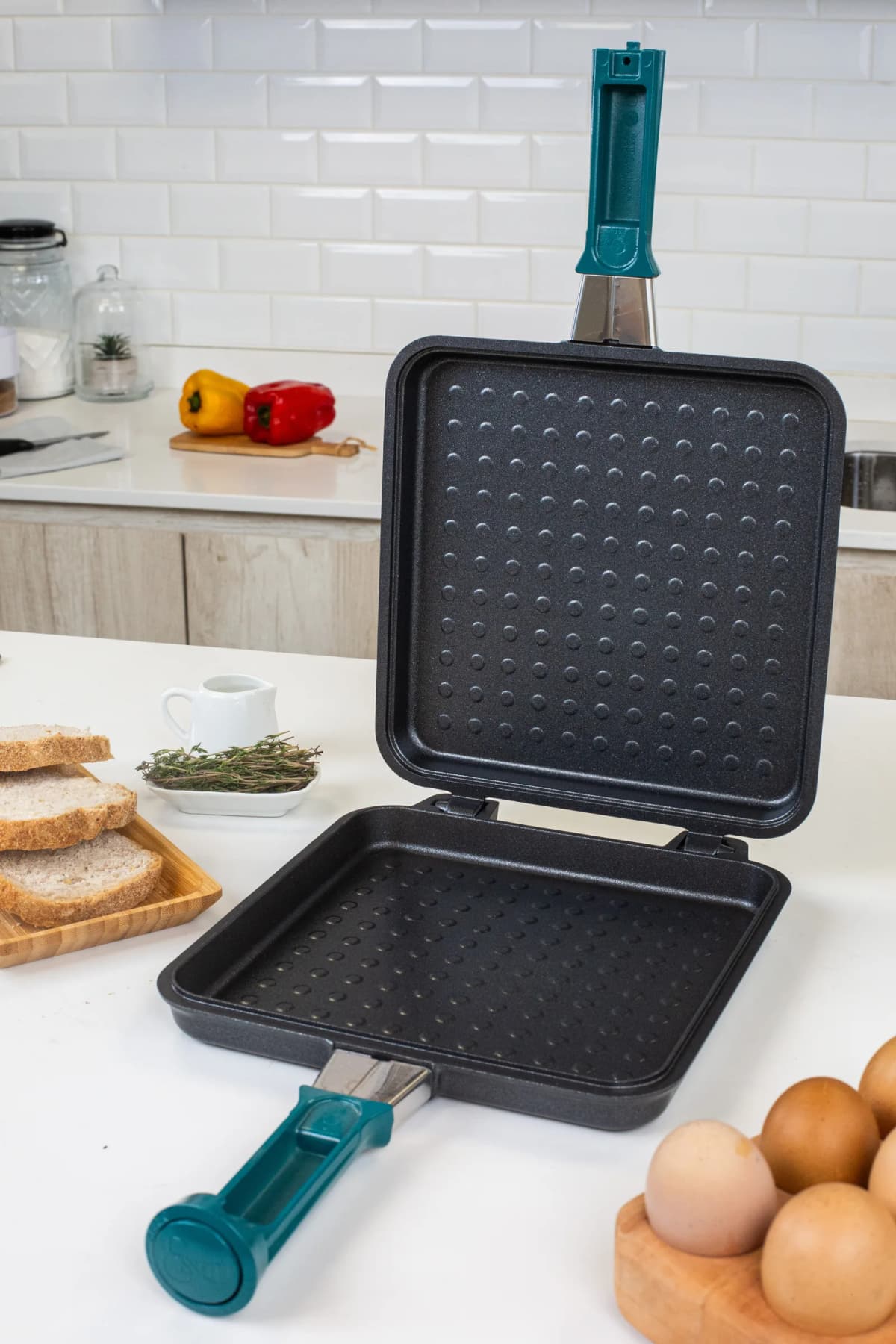 Una pieza Essen para tostados, abierta sobre la mesada, con pan y huevos al lado